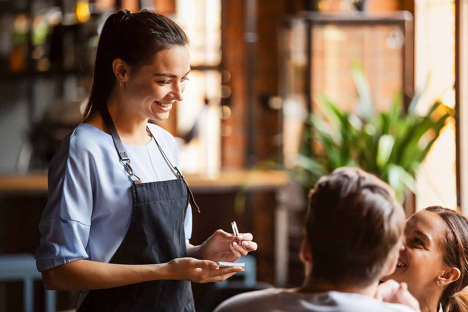 1199696833 Smiling female waitress take order talk to clients couple