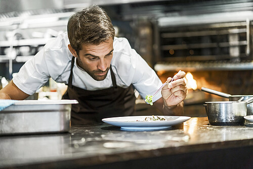 Male chef garnishing food in kitchen
