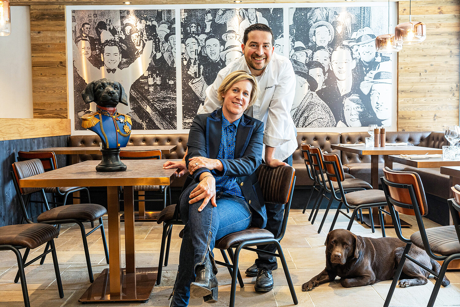 Sie geben dem Restaurant Casy in Crans-Montana ihren prominenten Namen: Das Gastgeber-Paar Caroline Ogi und Sylvain Stefanazzi Ogi mit ihrem Labrador Newton. Der Metallsiebdruck an der Wand im Hintergrund erinnert an das Ende der Prohibition in den USA: Endlich wieder mehr Freiheit — ein Wunsch, der in adaptierter Form auch aktuell zur Corona-Krise passt. Und wer genau hinschaut, entdeckt dort sogar Caroline, Sylvain und Hund Newton.