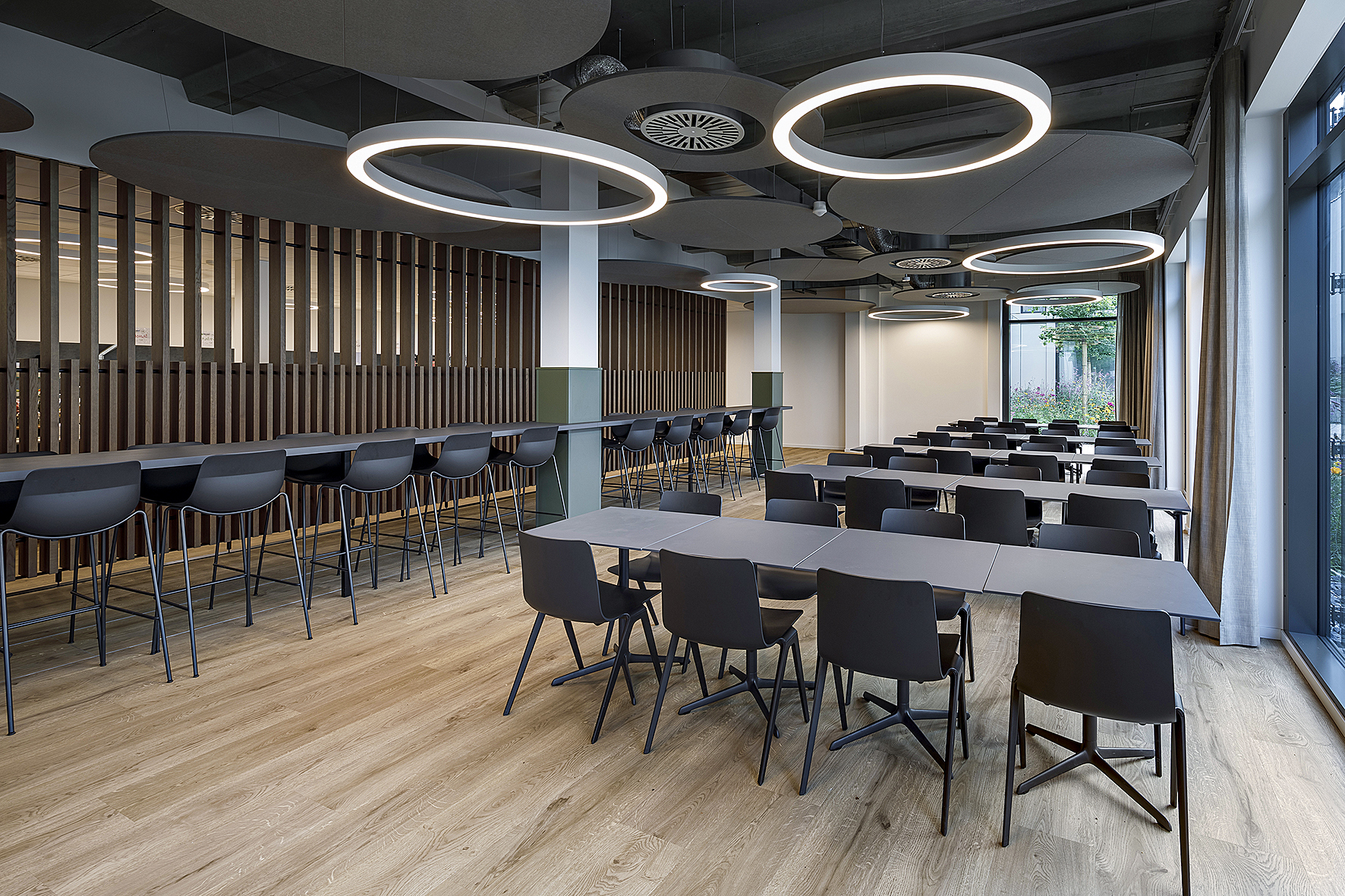 Lichtdurchlässig und leicht: Eine Lamellenwand aus Holz trennt das Bistro vom Free-Flow-Bereich.