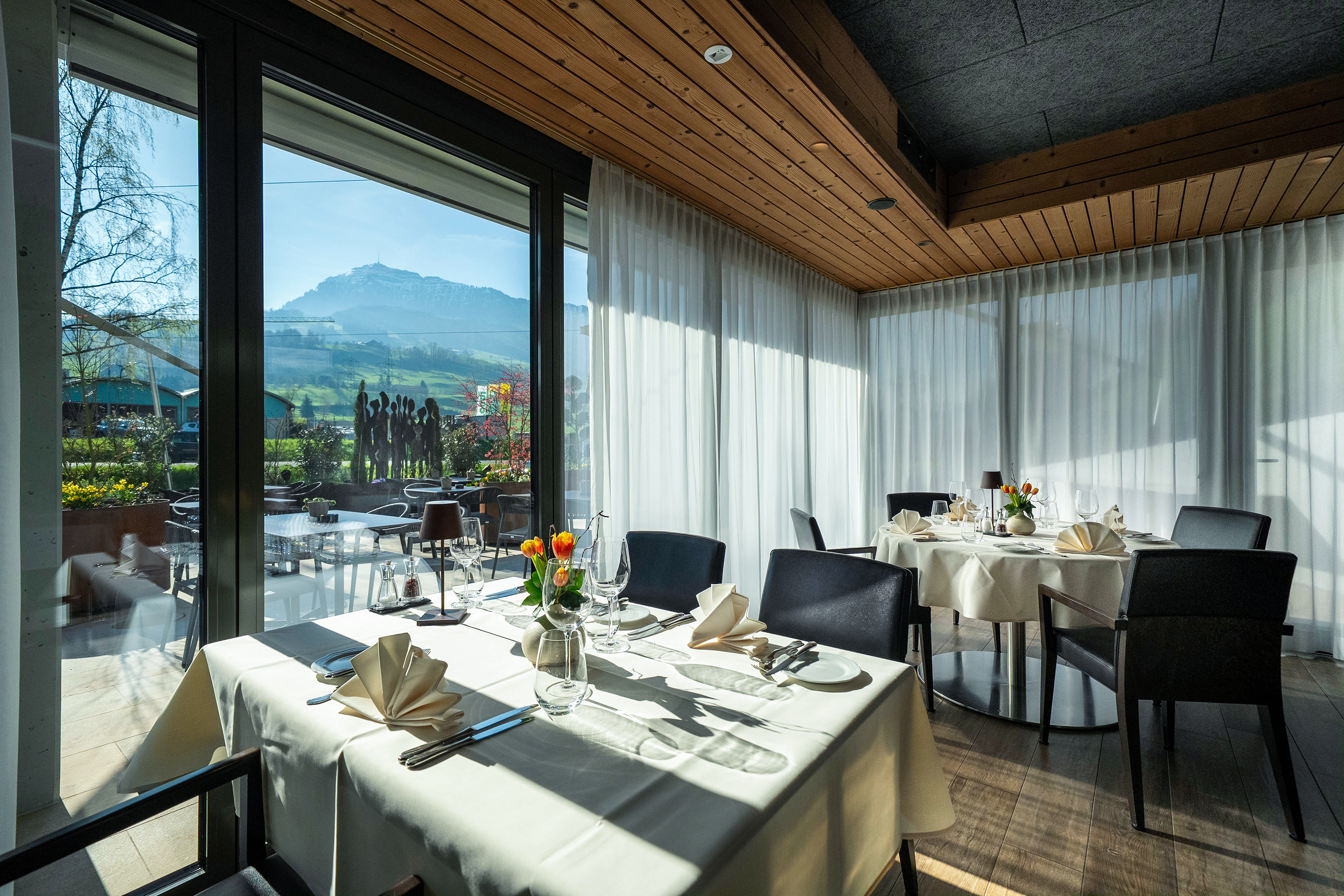 Im Wintergarten erwartet die Gäste weiss gedeckte Tische und ein schöner Blick auf die Rigi.