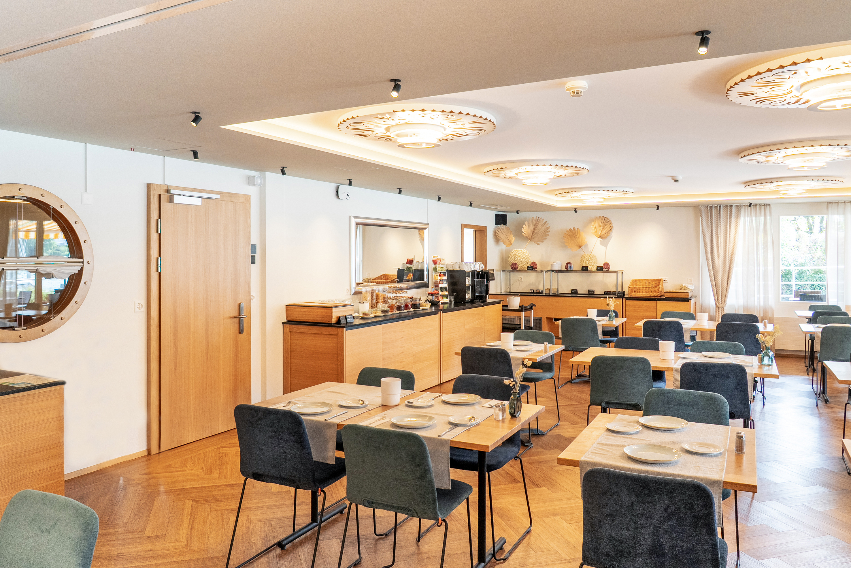 Akustisch wirksame Decken aus Stoff und Holz sorgen für Ruhe, während indirektes Licht, Spots und Dekorleuchten Akzente setzen.