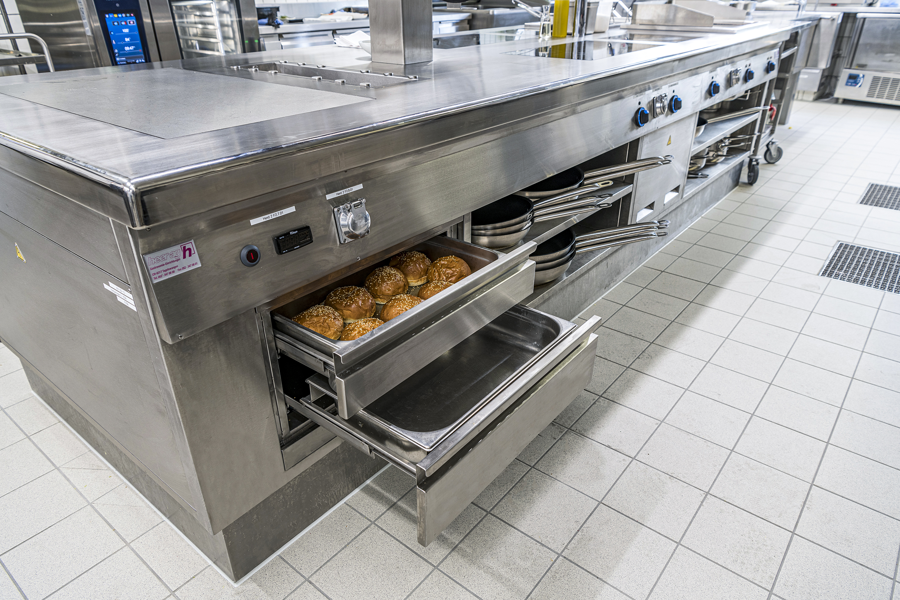 Chromstahlunterbauten mit viel Stauraum, unter anderem mit Warmschubladen und Halterungen für GN-Behältnisse.