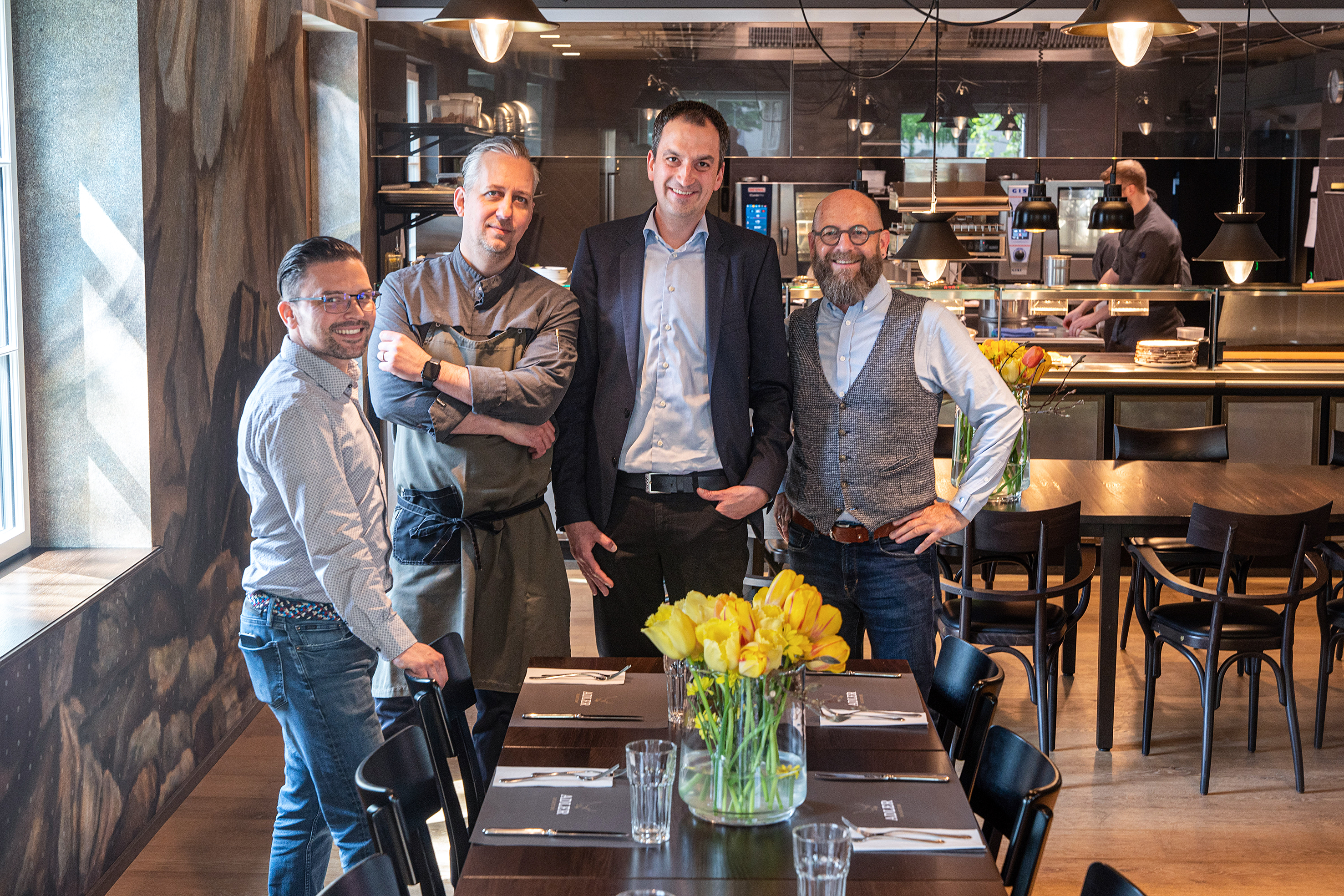 Im Herzstück des Drei-Häuser-Hotels Caspar, der Caspar-Wolf-Saal in seiner einzigartigen Bauholzweise, freuen sich die Beteiligten über eine gelungene Zusammenarbeit: Christian Loos und Daniel Mengelt (aussen) von der Firma planbar ag, Küchenchef Sebastian Rabe (links innen) sowie Gebietsverkaufsleiter Adrian Seeholzer von der Menu System AG (rechts innen).